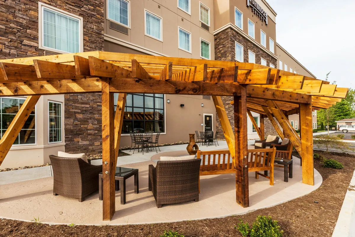 An inviting outdoor area with a wooden pergola, ample seating, stone walls, and planters. The space is designed for relaxation, socializing, and enjoying refreshments, ideal for gatherings or alfresco dining.